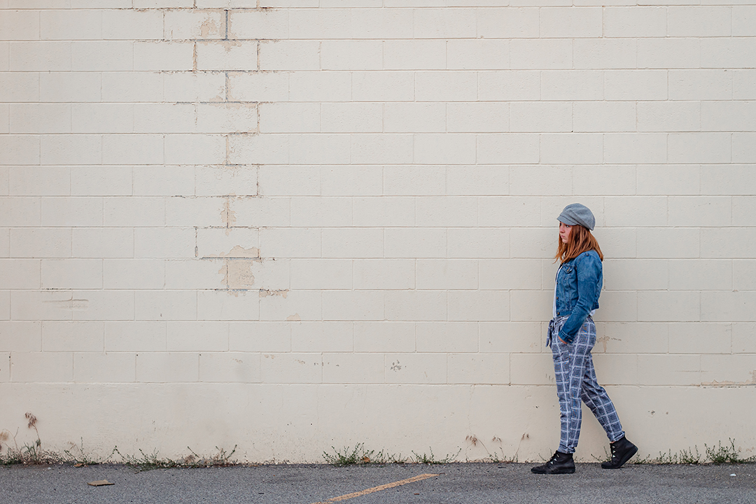 young woman in front of a white brick wall