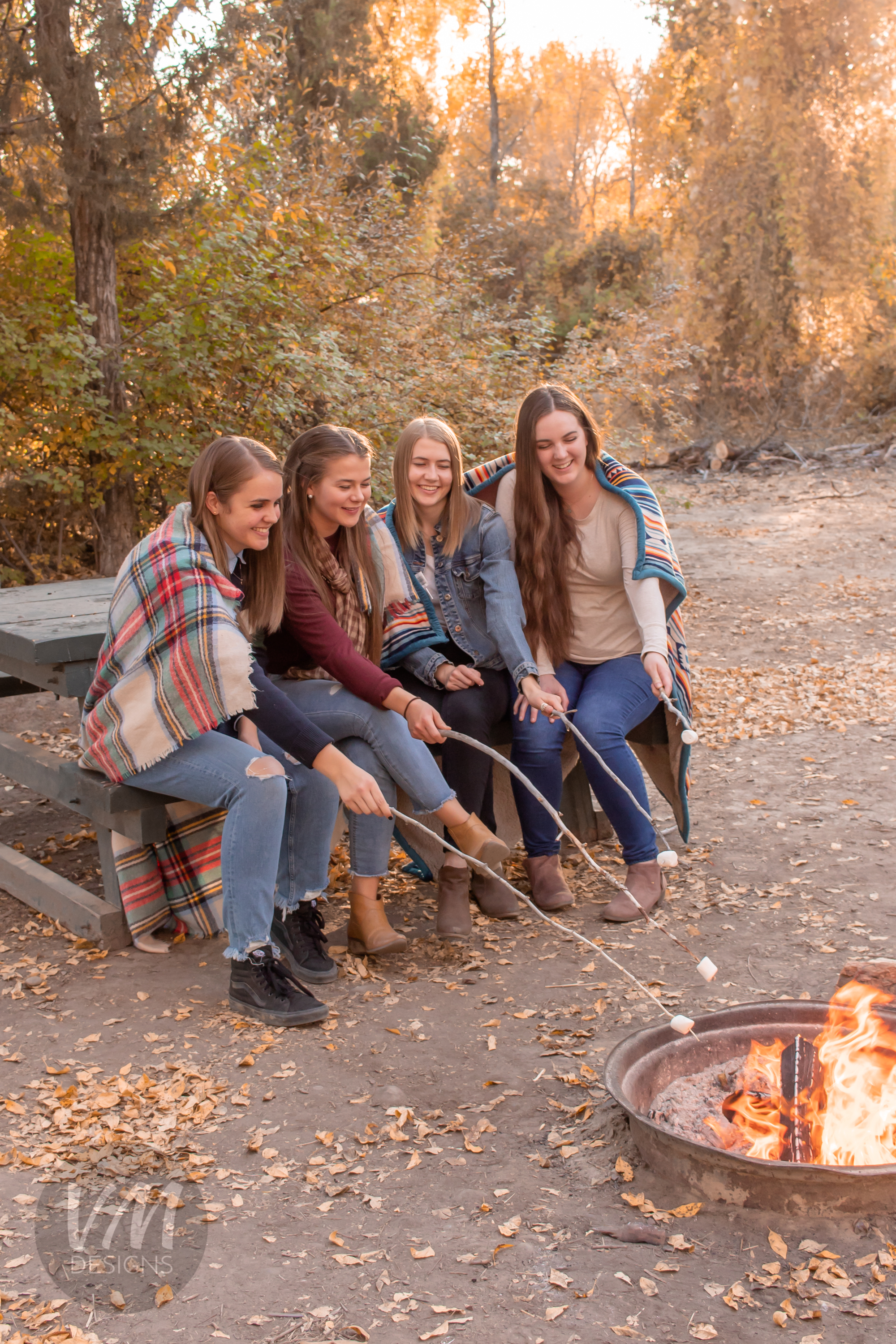 four young women sitting around a campfire