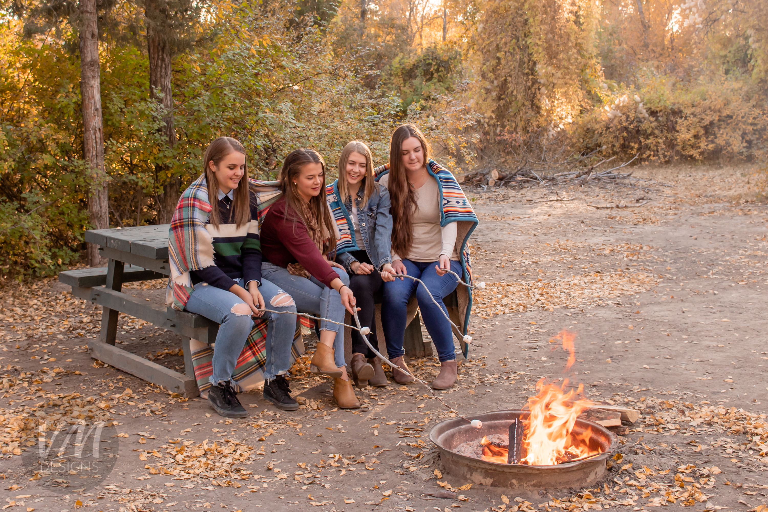 four young women sitting around a campfire